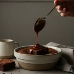 Cozy Dessert and Baking scene with a human hand drizzling chocolate sauce over a brownie in a ceramic bowl, warm natural light