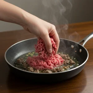 Browning ground beef with olive oil in a hot skillet.