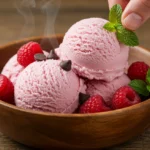 3-Ingredient Creamy Cottage Cheese Ice Cream-Melts Instantly A scoop of creamy pink low-carb cottage cheese ice cream in a wooden bowl, topped with raspberries and chocolate chips.