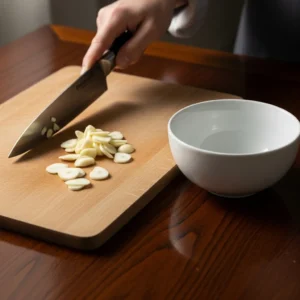 Chef knife slicing fresh garlic for spaghetti aglio e olio recipe.