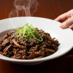 A completed bowl of easy 5-star Beef Bulgogi with steam rising, garnished with green onions and sesame seeds on a dark wood table.