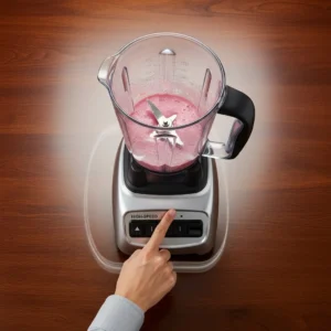 A hand pressing the high-speed button on a blender to mix a smoothie.