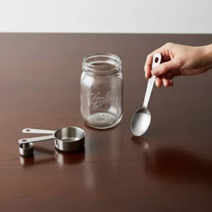A mason jar, measuring cups, and a tablespoon laid out for making overnight oats.