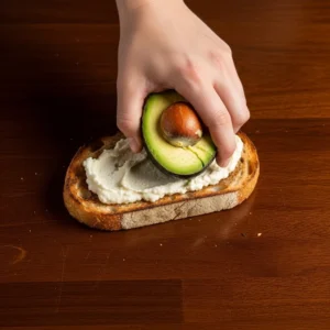 A hand mashing a ripe avocado directly onto a piece of crispy sourdough toast.