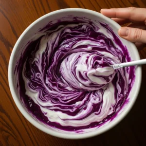 Purple cabbage and Greek yogurt mixed until glossy in bowl for low-calorie taco slaw