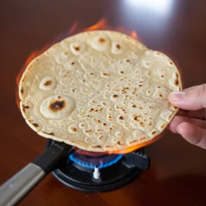 Corn tortilla warmed directly over gas flame with brown spots for shrimp tacos